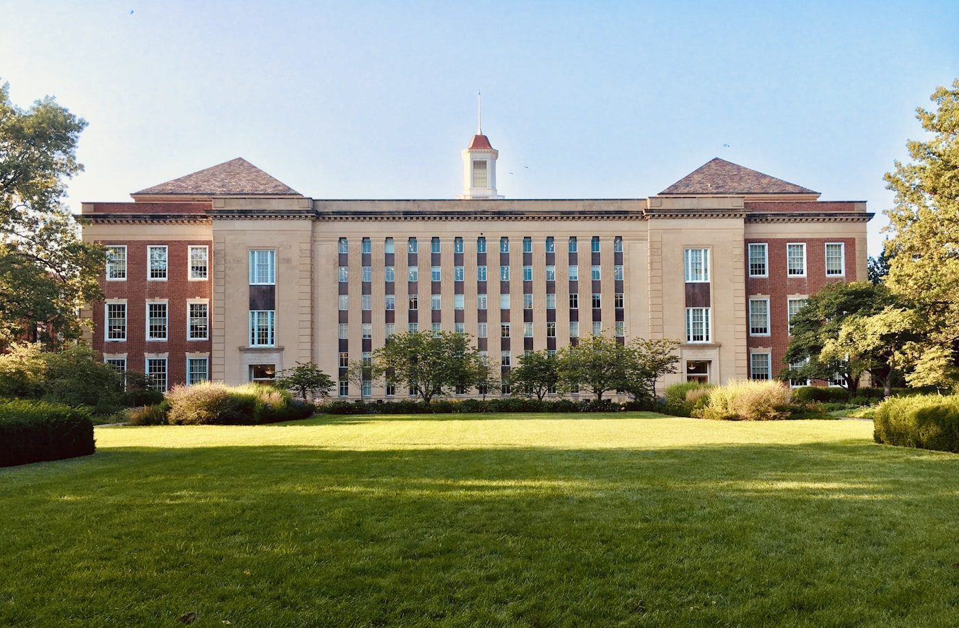 A historic collegiate building fronted by a green campus quad